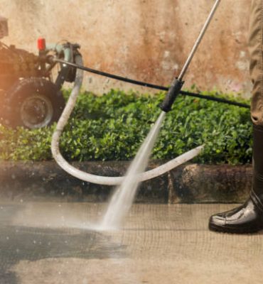 Worker cleaning driveway with gasoline high pressure washer ,professional cleaning services.