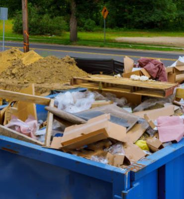 Industrial garbage bin blue construction debris container filled with rock and concrete rubble.